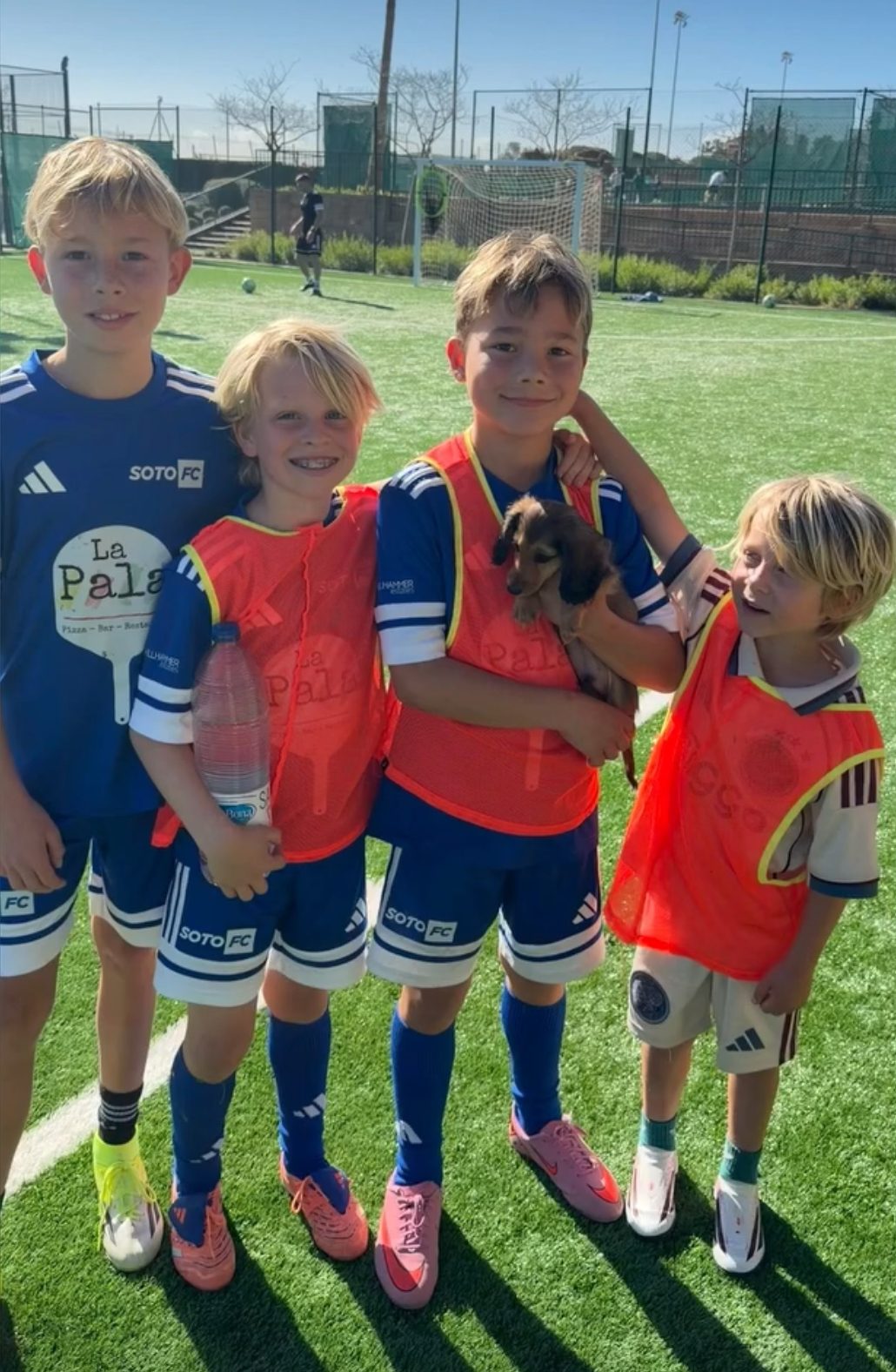 Four players in blue kit at the end of a session, one holding a puppy