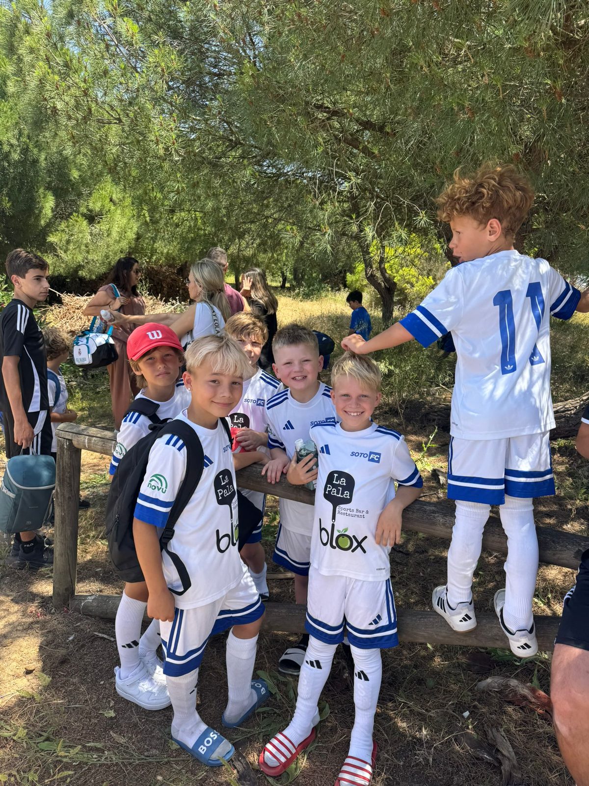 Players in white kit gathered in the shade between matches on a tournament day