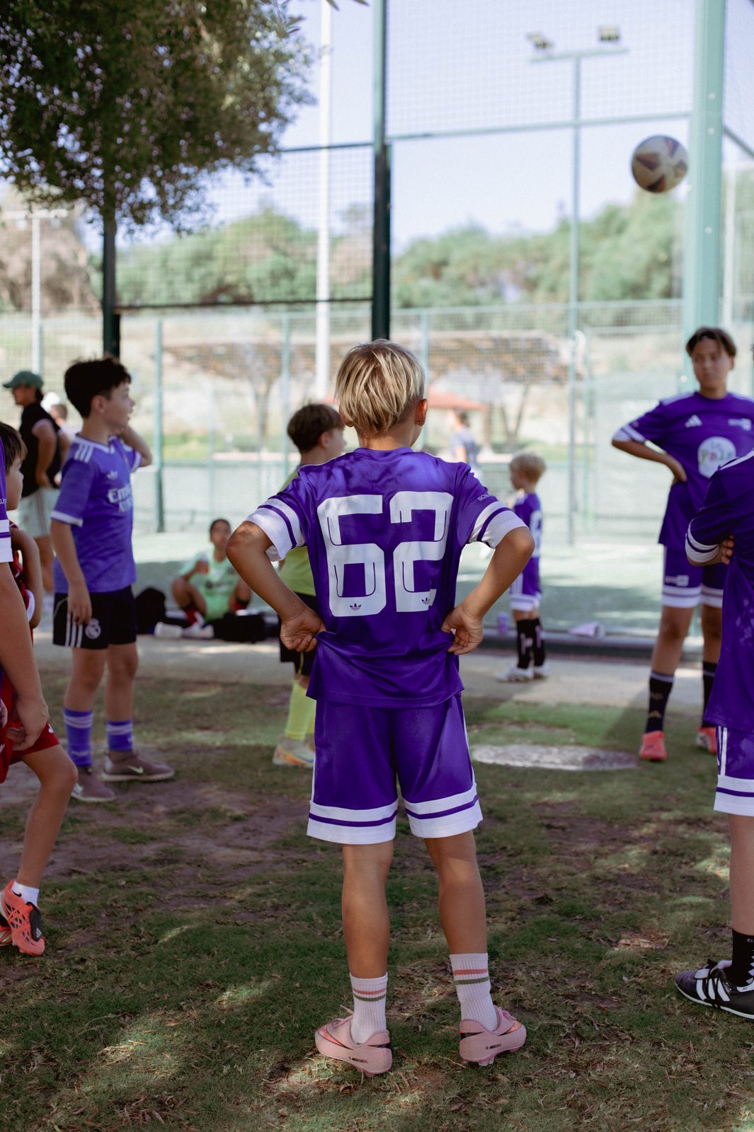 A player in purple watching from the edge of the pitch during a camp session