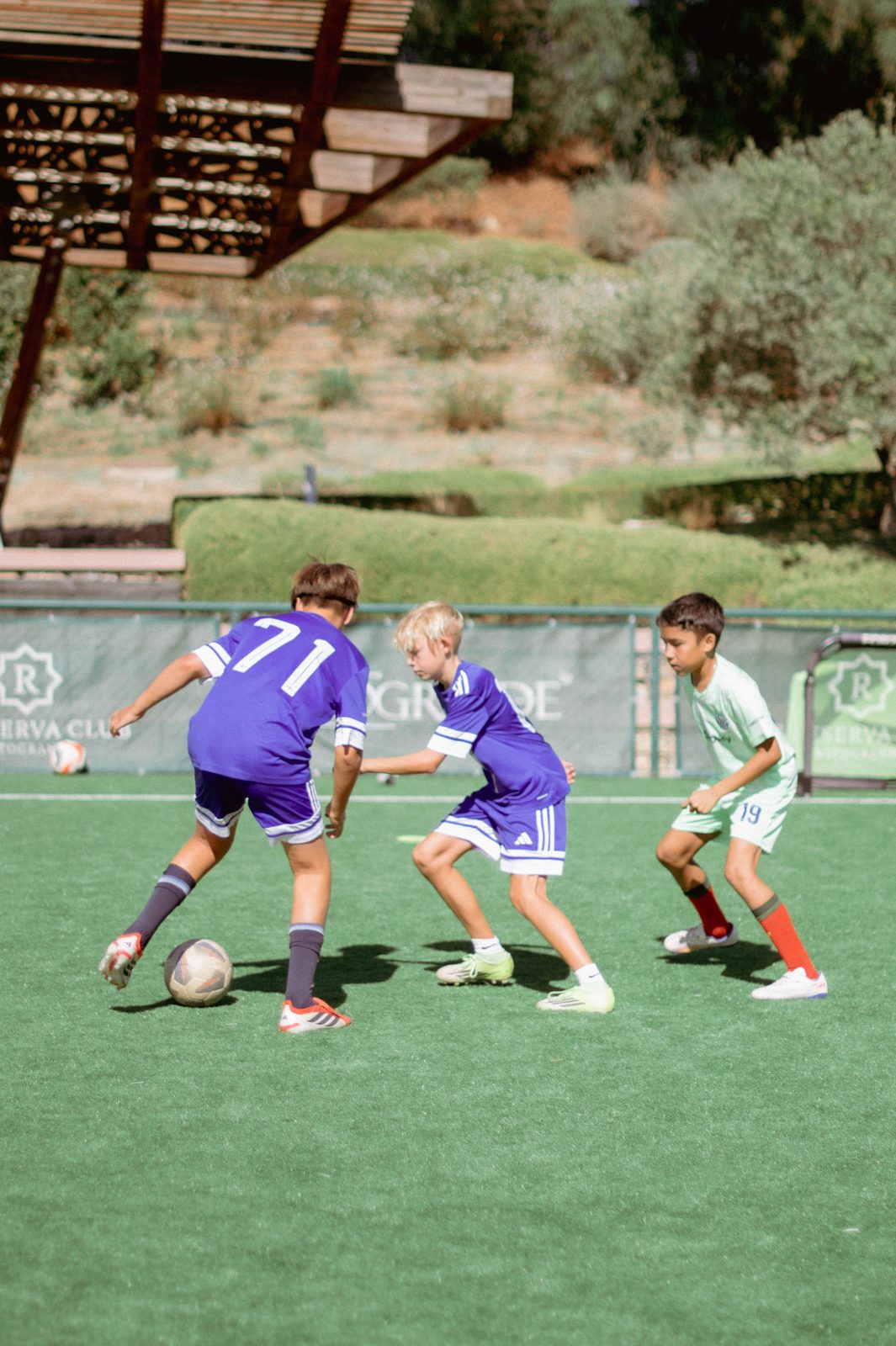 Three players competing for the ball during a camp match at La Reserva