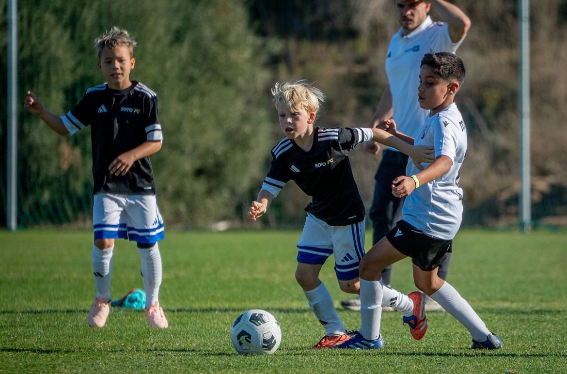 A player in the black Soto FC kit driving forward with the ball during a match